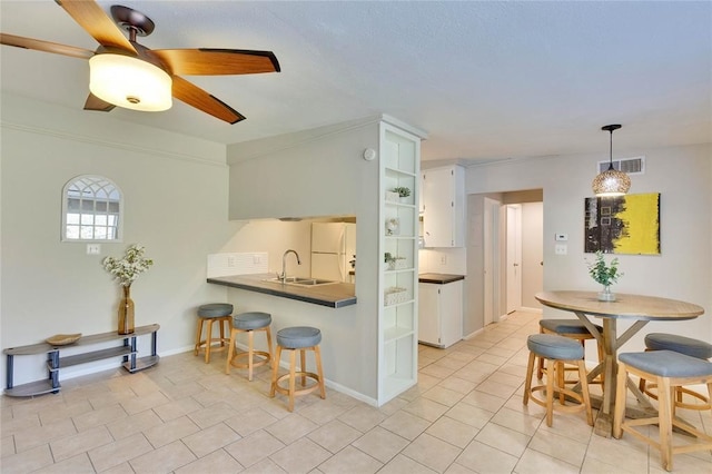 kitchen with a kitchen breakfast bar, white cabinetry, tasteful backsplash, white fridge, and kitchen peninsula