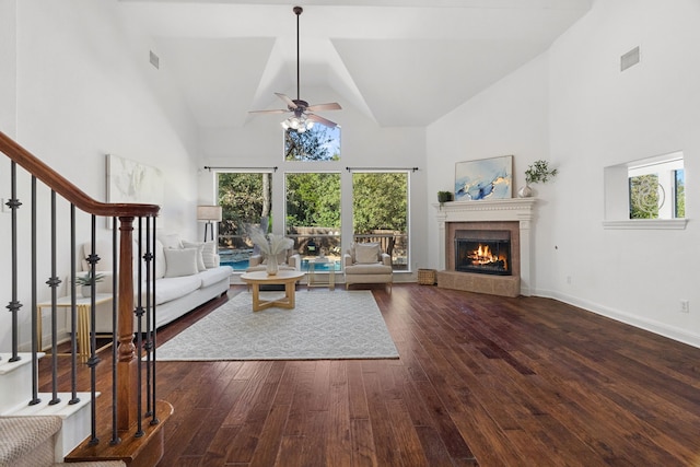 unfurnished living room with dark hardwood / wood-style floors, high vaulted ceiling, ceiling fan, and a tiled fireplace