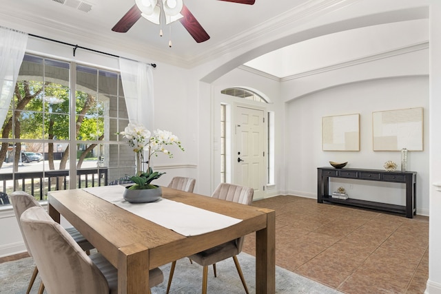 tiled dining room with ceiling fan and crown molding