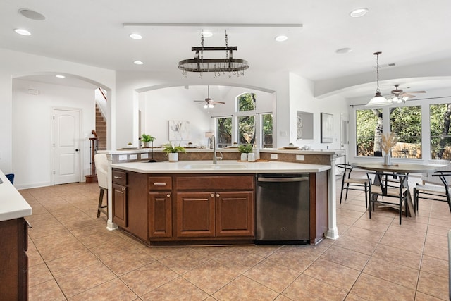 kitchen with stainless steel dishwasher, ceiling fan, sink, decorative light fixtures, and an island with sink