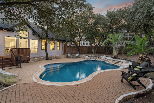 pool at dusk featuring a patio