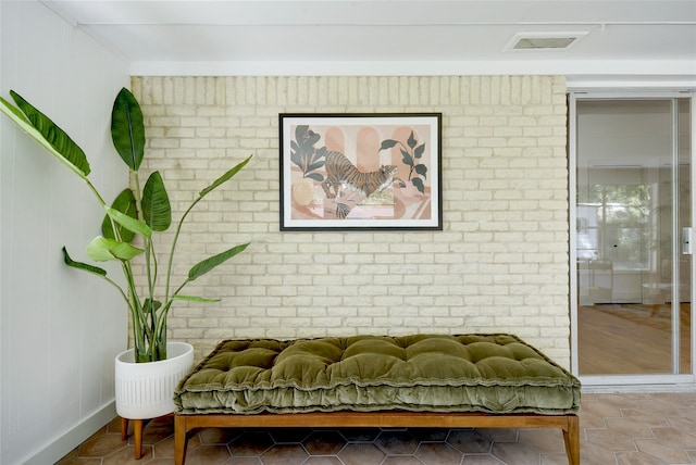 sitting room with tile patterned floors and brick wall