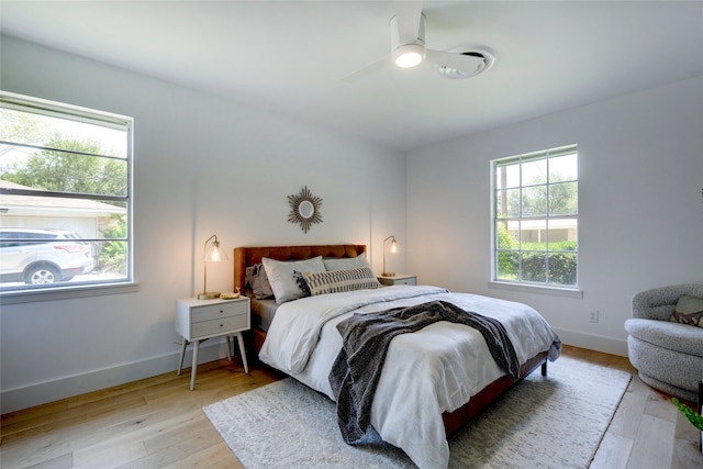 bedroom with ceiling fan, light hardwood / wood-style floors, and multiple windows