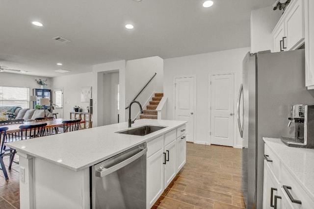 kitchen featuring stainless steel appliances, sink, a center island with sink, and white cabinets