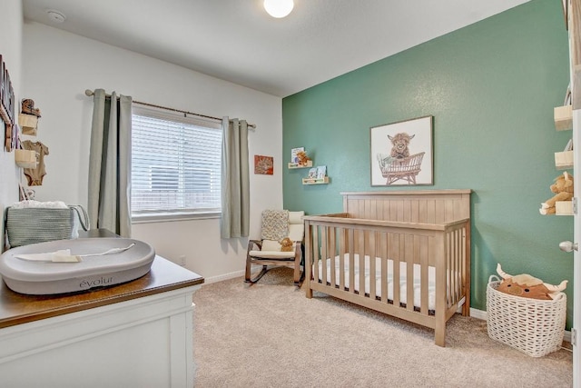 carpeted bedroom featuring a nursery area