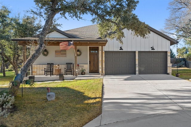 view of front of house featuring covered porch, a garage, and a front lawn