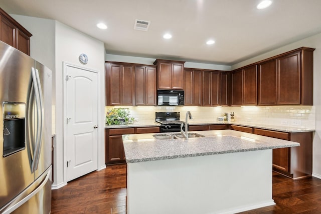 kitchen with black appliances, dark hardwood / wood-style floors, light stone countertops, and an island with sink