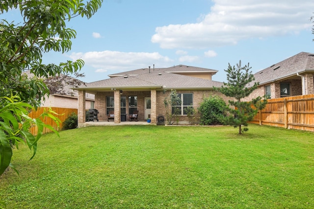 rear view of property with ceiling fan, a yard, and a patio