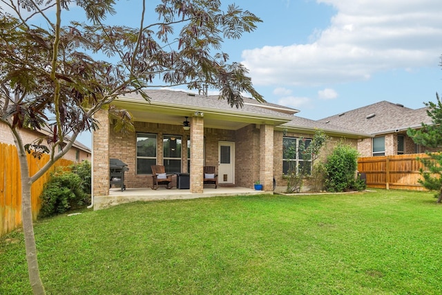 rear view of house with ceiling fan, a yard, and a patio