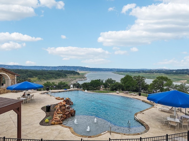 view of swimming pool featuring pool water feature, a water view, and a patio