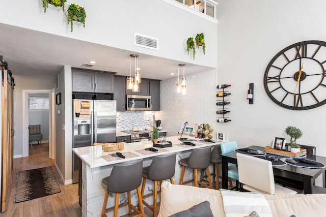 509 Short Circuit Unit 203, Horseshoe Bay, TX 78657 - kitchen featuring appliances with stainless steel finishes, a kitchen bar, tasteful backsplash, light wood finished floors, and light countertops