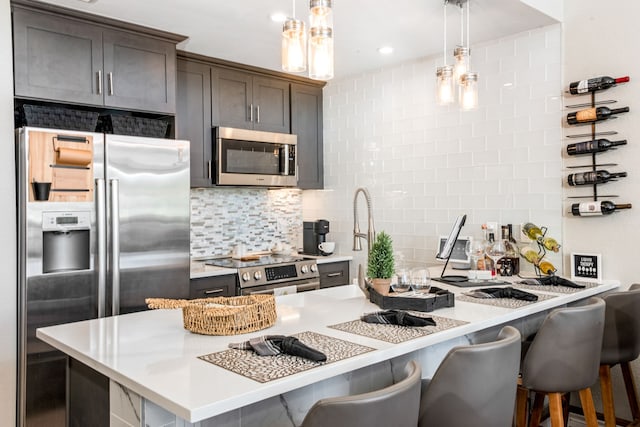 kitchen with a kitchen bar, backsplash, hanging light fixtures, and stainless steel appliances