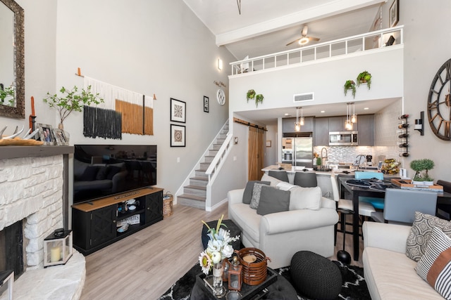 living room featuring ceiling fan, beam ceiling, light wood-type flooring, and high vaulted ceiling