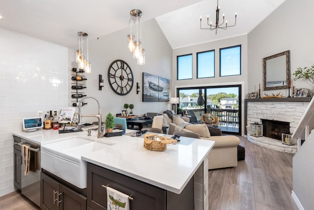 kitchen with kitchen peninsula, dark brown cabinets, sink, a fireplace, and light hardwood / wood-style floors