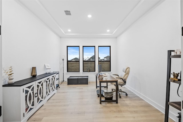 office with light hardwood / wood-style floors and a tray ceiling