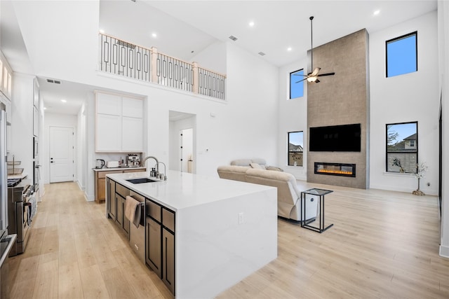 kitchen featuring white cabinets, a fireplace, sink, and a high ceiling