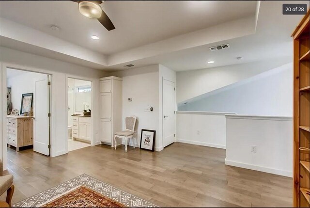 sitting room with ceiling fan, wood-type flooring, and a tray ceiling