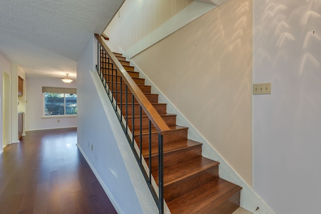 stairway with hardwood / wood-style floors and a textured ceiling