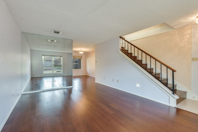 unfurnished living room with a textured ceiling and dark hardwood / wood-style flooring