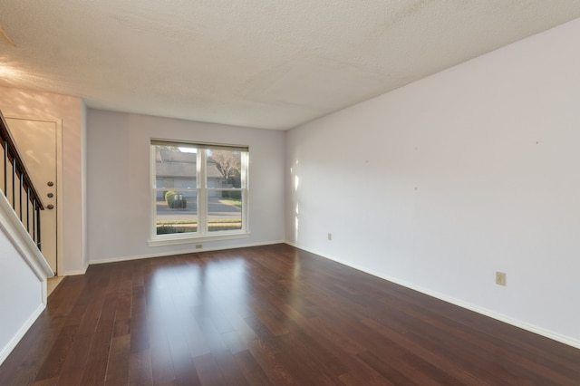 unfurnished room with a textured ceiling and dark hardwood / wood-style flooring