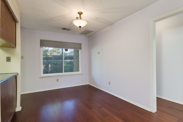 unfurnished dining area featuring dark hardwood / wood-style floors and a textured ceiling