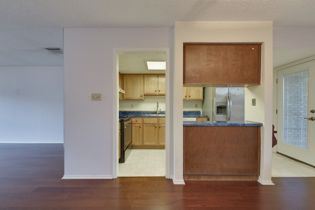 kitchen with sink, dark wood-type flooring, stainless steel refrigerator with ice dispenser, stove, and a textured ceiling