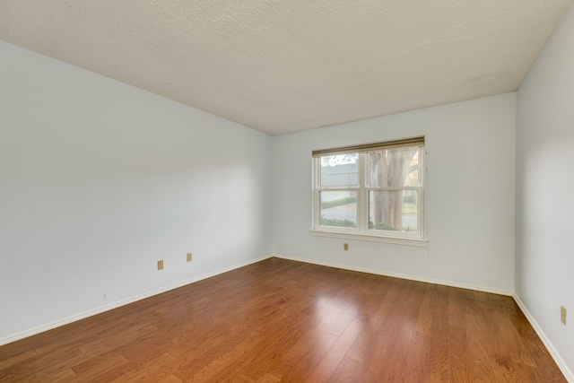 unfurnished room with hardwood / wood-style floors and a textured ceiling