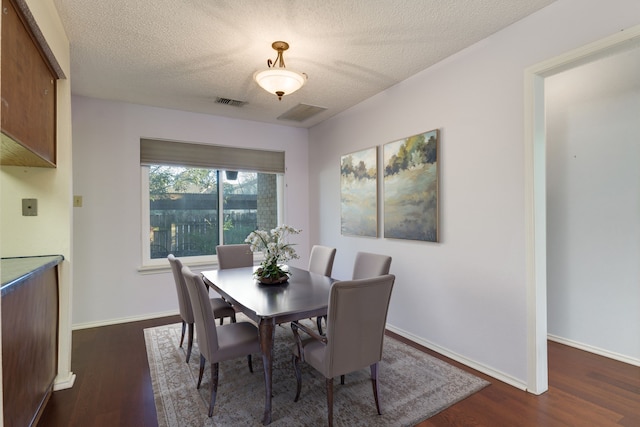 dining space with a textured ceiling and dark wood-type flooring