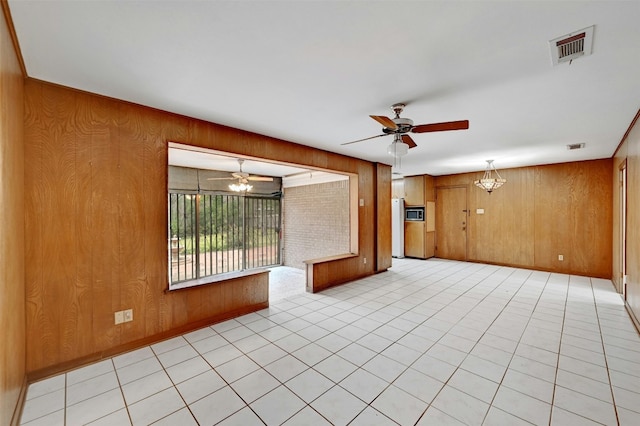 4204 Gregg Ward Ln, Austin, TX 78744 - empty room with wood walls, ceiling fan, a chandelier, and light tile patterned flooring