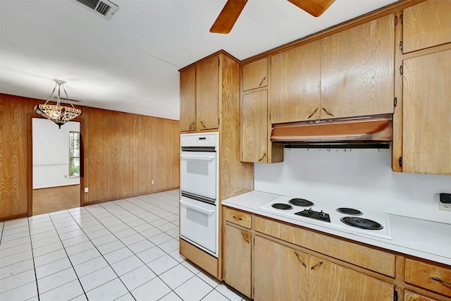 kitchen featuring wooden walls, light tile patterned floors, pendant lighting, and white appliances