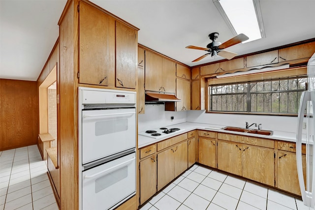 kitchen with wood walls, sink, light tile patterned floors, and white appliances