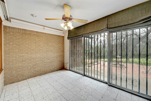 empty room with ceiling fan and brick wall