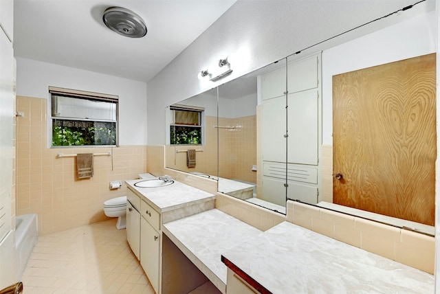 full bathroom with vanity, tiled shower / bath, tile patterned flooring, toilet, and tile walls