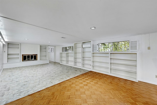 unfurnished living room featuring light parquet flooring, a brick fireplace, and a wall mounted AC