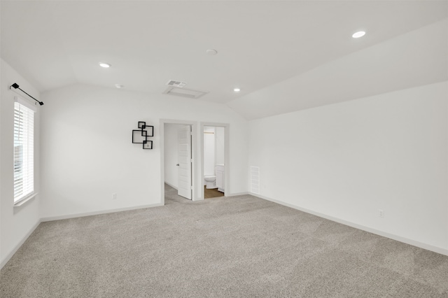 spare room with light colored carpet and vaulted ceiling