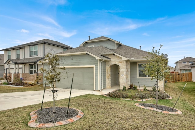 traditional-style house featuring an attached garage, fence, concrete driveway, roof with shingles, and a front yard