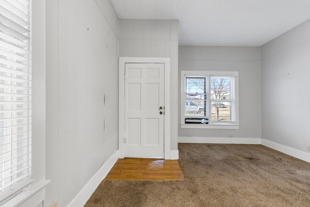 foyer with carpet floors and wood walls