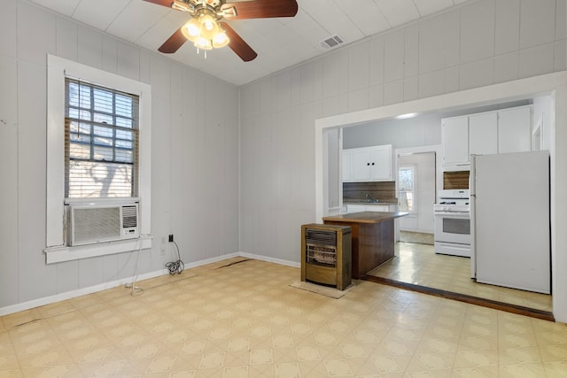 kitchen featuring white cabinets, white appliances, a wealth of natural light, and heating unit