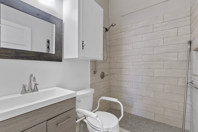 bathroom with tiled shower, vanity, and toilet