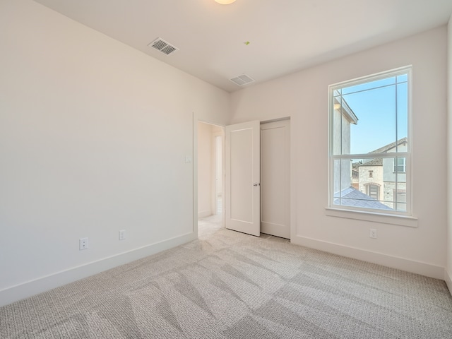 unfurnished room featuring a wealth of natural light and light colored carpet