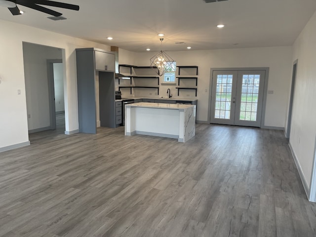 kitchen featuring gray cabinetry, stainless steel range with electric stovetop, french doors, hanging light fixtures, and hardwood / wood-style flooring