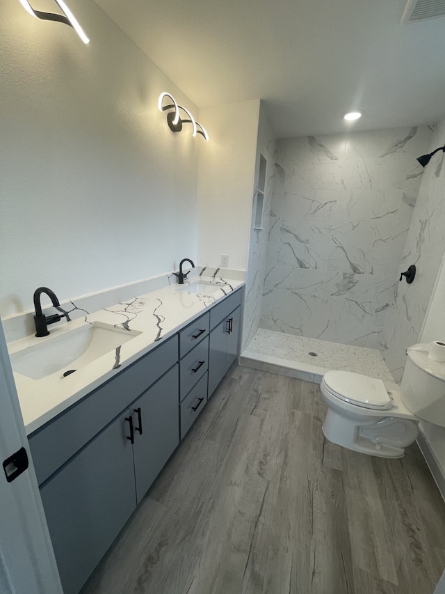 bathroom featuring tiled shower, hardwood / wood-style floors, vanity, and toilet