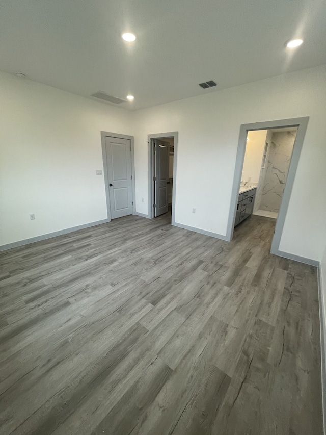 unfurnished bedroom with ensuite bathroom and light hardwood / wood-style floors