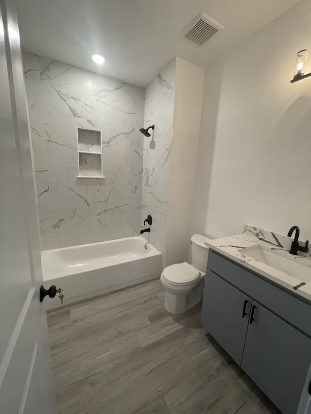 full bathroom with hardwood / wood-style flooring, vanity, toilet, and tiled shower / bath