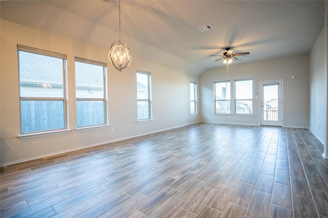 spare room with hardwood / wood-style floors, ceiling fan with notable chandelier, a wealth of natural light, and lofted ceiling