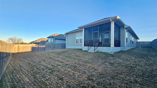 rear view of property with a sunroom and a yard