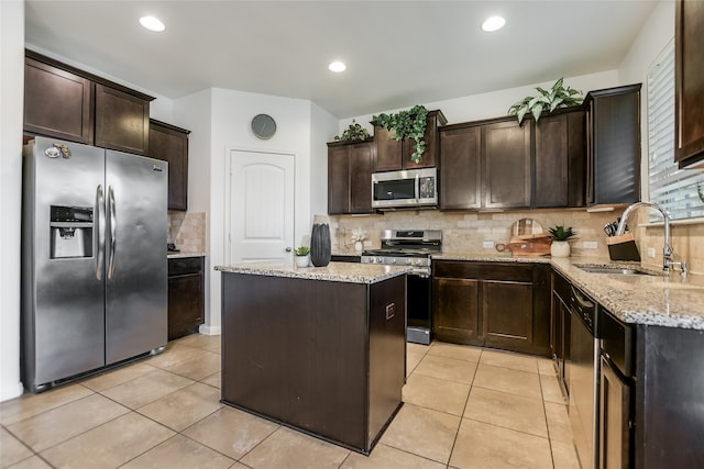 kitchen with appliances with stainless steel finishes, tasteful backsplash, dark brown cabinets, a kitchen island, and sink