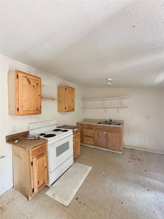 820 Chihuahua St, Lockhart, TX 78644 - kitchen with white range with electric cooktop, open shelves, a sink, a textured ceiling, and light floors