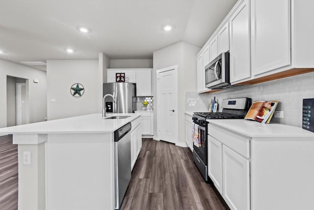 kitchen featuring dark wood-type flooring, stainless steel appliances, an island with sink, and white cabinets