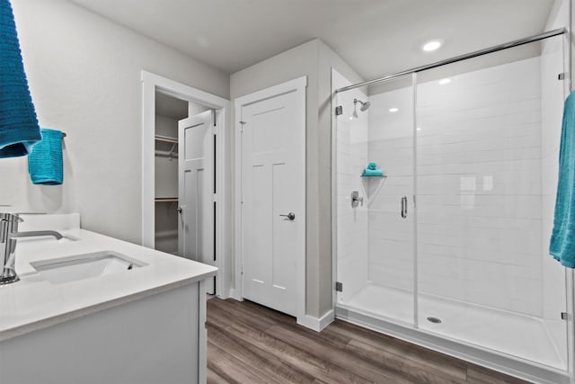 bathroom with hardwood / wood-style floors, vanity, and an enclosed shower